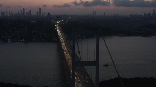 Estambul 15 de julio Mártires Puente del Bósforo al anochecer o de noche con City Skyline Silhouette y el tráfico de coches que fluyen fuera de las luces de la ciudad, Deslizamiento aéreo a la derecha — Vídeo de stock