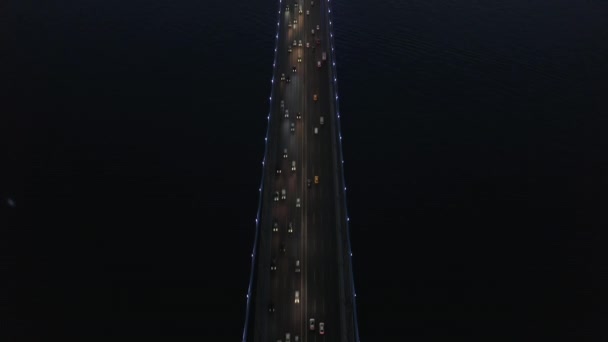 Ptačí oko shora dolů Pohled na most v noci s automobilovou dopravou při pohledu nahoru odhalující siluetu města, letecký sklon nahoru — Stock video