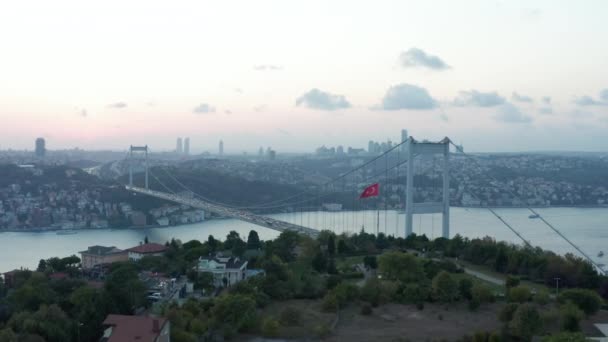 Turecká vlajka vlnění ve větru před mostem Istanbul Bosphorus a panorama města při západu slunce, zřízení letecké skluzavky vpravo — Stock video