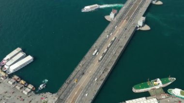 İstanbul 'da Boğaz' da Galata Köprüsü 'nden geçen toplu taşımacılık tramvayı, suda martılar ve tekneler, alçak açılı havadan çekim