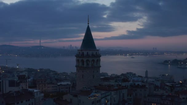 Silhouette de la tour Galata à l'heure bleue avec Bosphore en arrière-plan et ciel violet rouge, glissière aérienne à gauche — Video