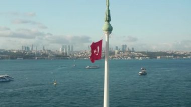 İstanbul 'daki Su Çemberindeki Bakireler Kulesi' nin tepesinde dalgalanan canlı Kızıl Türk Bayrağı, havada daireler çizen çekim