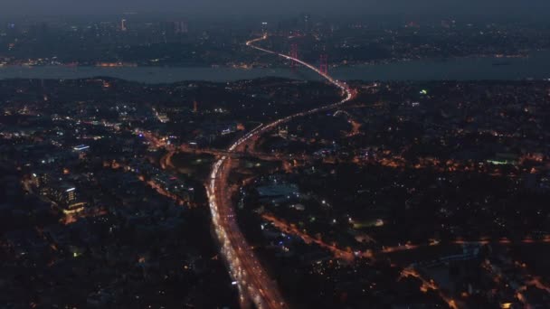 Highway Freeway Road durch Istanbul City mit rot erleuchteter Bosporus-Brücke in der Ferne bei Nacht, Luftaufnahme — Stockvideo