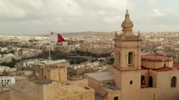 Hermoso castillo de arena Gozo Fort con bandera de Malta ondeando revelando campo de Gozo Island, muñeca aérea hacia adelante — Vídeos de Stock