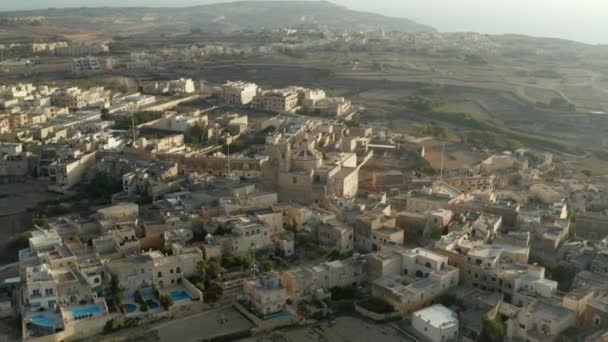 Kirche inmitten einer kleinen Mittelmeerstadt in beige und brauner Sandfarbe auf Malta, Drohnenperspektive, Dolly vorwärts — Stockvideo