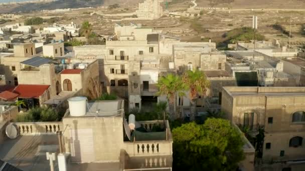 Häuser mit Sonnenkollektor und Dachterrasse im mediterranen Land Malta in brauner und beiger Sandfarbe mit Blick auf Land und Kirche, Antenne Dolly — Stockvideo