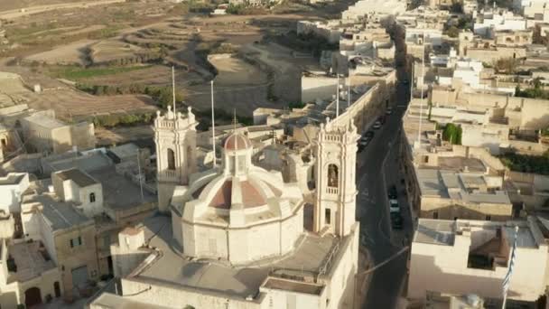 Brown Beige Church on Small Mediterranean Town Village Interchange Road through City on Malta, Gozo Island from Aerial Drone Perspectief slow dolly forward — Stockvideo