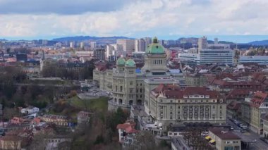 Şehir merkezine yerleştirilmiş Bern Federal Sarayı 'nın hava görüntüsü, İsviçre' nin tarihi hükümet binası. Etrafı bulutlu gökyüzü ve şehir planlarıyla çevrili..