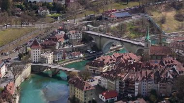Tarihsel Bern şehir manzarası Nydeggbrucke köprüsünün turkuaz Aare nehrine yayılışını gösteriyor, yukarıdan bakıldığında ortaçağ kentsel manzarasını ortaya çıkarıyor.
