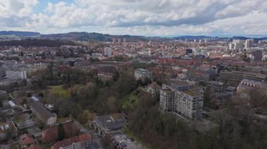 Bern, İsviçre 'nin panoramik hava manzarası, konut binaları, yeşil alanlar ve kışın uzak şehir manzarası.