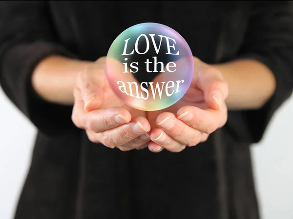 愛は常に答えの単語愛は答えを含む女性の手のひらの上に浮かんで大きな透明ボールです — ストック写真