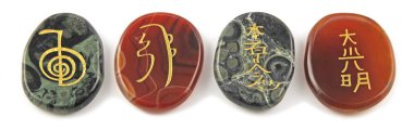 Dört büyük Reiki şifa Carnelian ve Kambaba Jasper palm taşlar kazınmış sembolleri - beyaz bir arka plan karşı temiz üste yerleştirilir