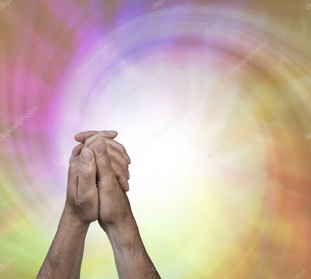 The power of prayer - male hands in prayer position with a large white spiralling vortex flowing from his hands against a pink orange and lime green energy background with copy space