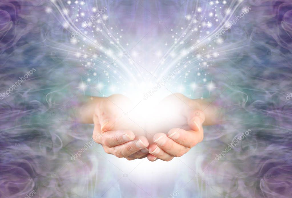 Sending High Resonance Healing Energy - female cupped hands emerging from a lilac blue swirling energy field background with shimmering sparkles white light and copy space                              