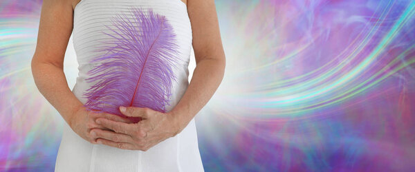 Я утверждаю, что я достаточно сильная женщина в белом платье держа большое лиловое перо страуса против эфирного розового и синего образования энергии с копировальным пространством
