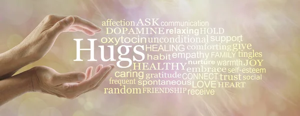 8 hugs a day keeps the doctor away - female hands cupped around the word HUGS surrounded by a word cloud against a warm orange coloured bokeh background