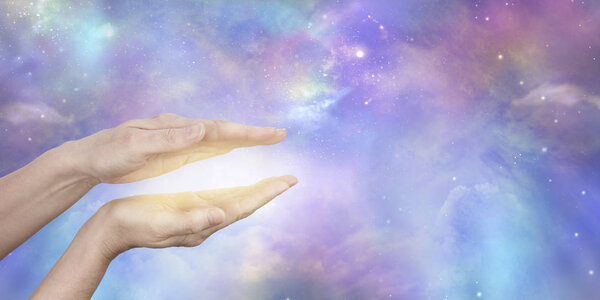 Отправка энергии космического исцеления - женские руки, удерживаемые в параллельном положении с золотым светом между ними на прекрасном небесном фоне неба с копировальным пространством

