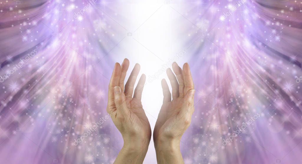 Bathing Hands in Beautiful Healing Resonance  - female cupped hands reaching up into a stream of white light with shimmering sparkles flowing down on a radiating pink ethereal energy formation background with copy space