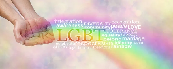 LGBT awareness word tag cloud - male hands in open cupped position with a rainbow flowing outwards and an LGBT word cloud  beside on a soft peach bokeh background