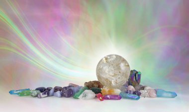 Rutilated Quartz Kristal Küre Arkaplan - güzel büyük kuvars topu çeşitli yuvarlanmış iyileştirici taşlarla çevrili ruhani pembe bir yeşil enerji oluşumuna karşı fotokopi uzayı ile