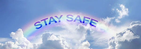 Stay Safe arcing rainbow campaign background - wide blue sky with clouds and rainbow and the words STAY SAFE matching the arc of the rainbow with copy space