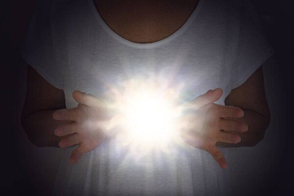 Исцеляющая энергия Феномен - женщина в белой тунике с руками на уровне груди с ярким сияющим белым светом шара между 