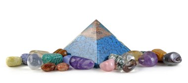 Orgon piramit gücü ve iyileştirici kristaller - bakır spiral ve açık kuvars, Orgone piramidinin içindeki mavi yonga taşlarının üzerinde, beyaz arka planda izole edilmiş karışık iyileşme taşlarıyla çevrili.