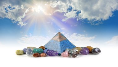 Orgon piramit gücü ve iyileştirici kristaller güneş ışığı flaması - bakır spiral ve mavi yonga taşlarının üzerinde Orgone piramidinin içinde karışık devrilmiş iyileştirici taşlarla çevrili kuvars 