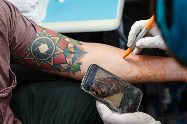 纹身师 在纹身 艺术概念和设计实现之前 在皮肤上使用手机和铅笔进行设计 — 图库照片