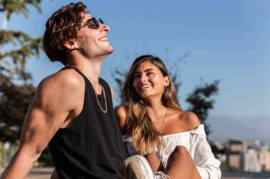 Genç, beyaz, aşık bir çift oturur, oynar, güler ve açık havada aşk, park, arka, moda kavramını paylaşır.