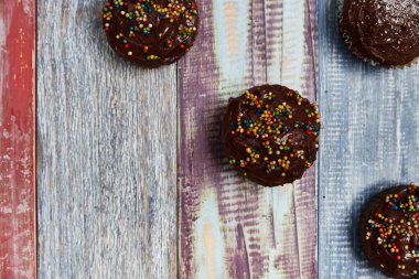 Bir bebek partisi için renkli panoların arka planında ve sağ tarafında süslemeleri olan çikolatalı kekler, yukarıdan çekilen fotoğraf, parti konsepti, arka plan, renkler, ahşap, pastalar