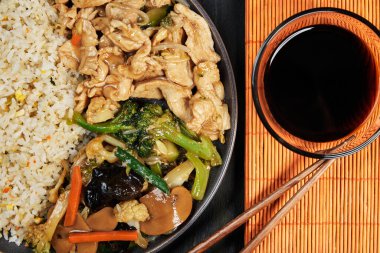 Gri bir tabakta servis edilen Çin yemeği soya sosu ve portakal rengi masa örtüsünün üzerinde yemek çubukları ve koyu ahşap tahta, etnik gıda konsepti.