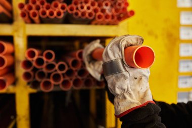Bir araç olarak işinin ortasında maske, eldiven ve miğfer takan genç bir kadın ve yeni normal bir modelde PVC tüpleri kullanan bir malzeme satıcısı.