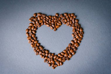 Kalp çemberi, papatya çiçekleri içinde kahve çekirdeğinden yapılmış gri mavi bir arka plan modeli.