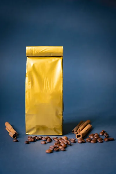 Kahve kesesi, kruvasan ve koyu mavi arka planda fasulyeli süt. Altın kağıt temiz çanta.