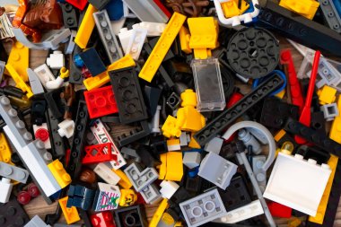 Renkli plastik tuğlalar, arabalar ve siyah kağıttaki oyuncakların detayları. Oyuncaklar için küçük, parlak yedek parçalar.
