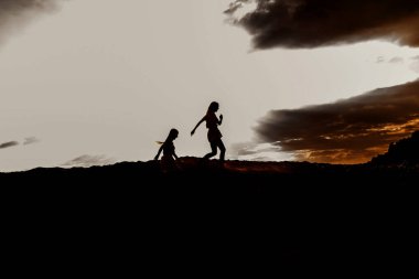 Kumsalda gün batımı ve aile, sahildeki insanların siluetleri, başarı ve aile birliği.