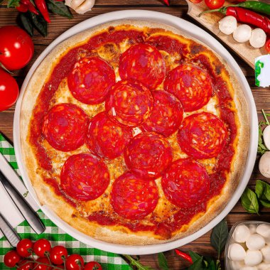 Lezzetli taze biberli pizza ve ahşap arka planda domates fesleğeni. Pepperonili pizzanın en iyi manzarası. Düz yatıyordu. Metin için kopyalama alanı ile. Pankart