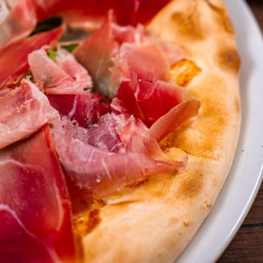 Jambonlu pizza, roka ve parmesan peyniri.