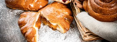 Fırın, çeşitli ekmek çeşitleri. Ekmek ruloları, baget, bagel, tatlı çörek ve kruvasan yukarıdan yakalanır (düz yatak). Siyah arkaplan, bedava kopyalama alanı. Yatay pankart düzeni.