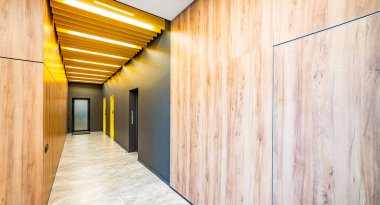 Ofis binasında uzun bir koridor manzarası. Koridordaki tuvaletlerin kapıları. WC işaretli kapılar. Fabrikanın tuvaletlerine giriş.