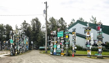 Yukon, Kanada Watson Gölü işareti yazı ormanda bir görüntü. Ziyaretçi-ebilmek eklemek onların kendi işaretleri üzerinden 80.000 zaten mevcut.