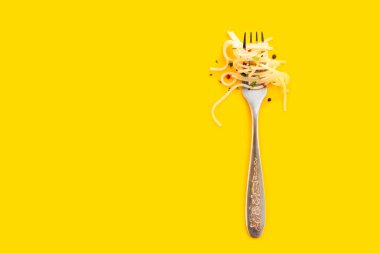 Sarı arka planda çatala sarılı spagetti.