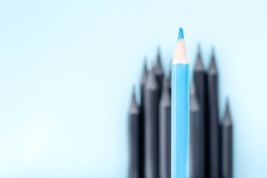 Bulanık siyah kalemlerin arkaplanına odaklanmış bir mavi kalem