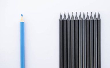 bir sürü siyah kalem ve beyaz arkaplanda bir mavi kalem.