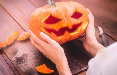 Bir kadının elinde bir balkabağı feneri