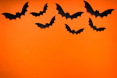 Parlak turuncu arka planda siyah yarasalar