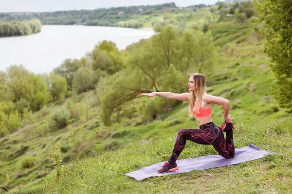 Slim mulher desportiva está fazendo exercícios de fitness ao ar livre no parque da natureza . — Fotografia de Stock