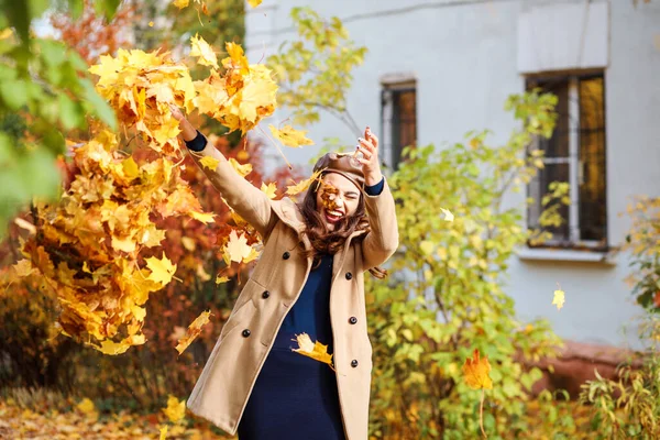 Schöne Frau amüsiert sich im Herbst im Freien und spielt mit Herbstblättern. — Stockfoto