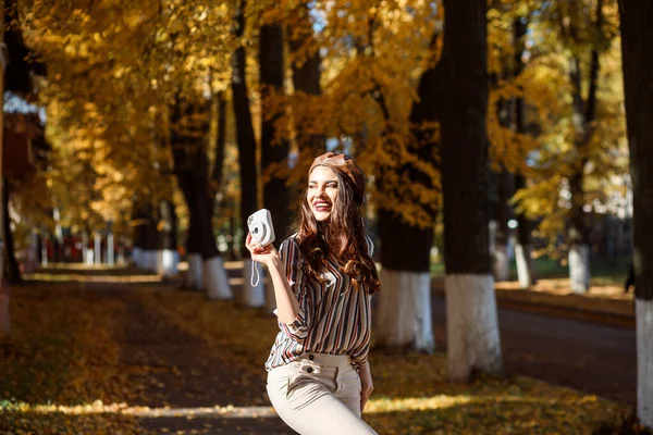 Modische Frau fotografiert mit ihrer Sofortbildkamera. Im Herbst im Freien. — Stockfoto